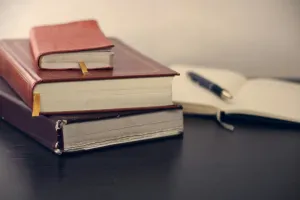 Selective focus of three books beside an opened notebook.